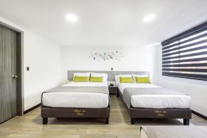three beds in a room with white walls and yellow pillows at Ayenda 1024 Agora Inn Hotel in Bogotá
