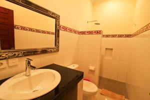 y baño con lavabo, espejo y aseo. en Awan Bali House, en Ubud