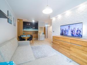 a living room with a large flat screen tv on a brick wall at Apartament Turkusowy in Ustronie Morskie