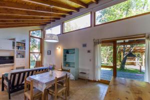 Una sala de estar con mesa y sillas y ventanas. en Casa Las Lilas, en Villa La Angostura