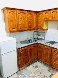 a kitchen with wooden cabinets and a white refrigerator at Efigenia playa/mar 1 in Valle Gran Rey