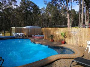 a swimming pool in a backyard with a fence at Vineyard Hill in Lovedale