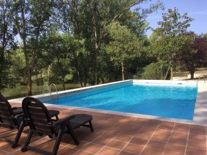 una piscina con 2 sillas y una mesa en Can Guixera, en Porqueres