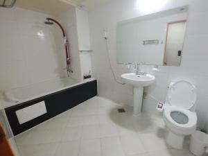 a bathroom with a toilet and a sink and a tub at New Grand Hotel in Daegu