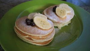 two pancakes with bananas and blueberries on a green plate at Home-Bience Hostel in Uluwatu