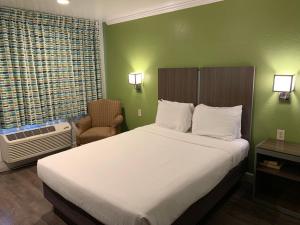 a bedroom with a bed and a chair and a window at Gilroy Inn in Gilroy