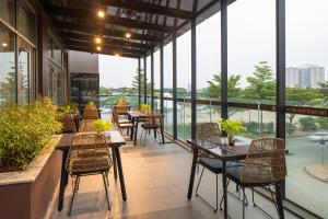 a restaurant with tables and chairs and windows at Ibis Saigon South in Ho Chi Minh City