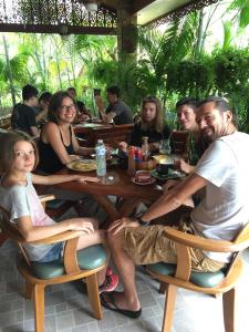 um grupo de pessoas sentadas em torno de uma mesa de madeira em TR Guesthouse em Sukhothai