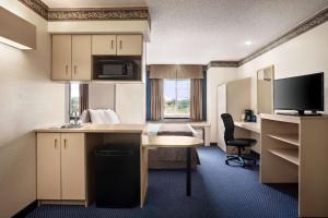 a hotel room with a desk and a bed at Travelodge by Wyndham Fort Scott in Fort Scott