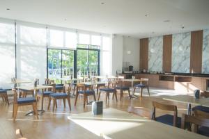 a dining room with tables and chairs and windows at Donchan Grand Hotel in Chiang Mai
