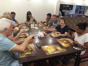 un grupo de personas sentadas alrededor de una mesa comiendo comida en Sauraha Resort, en Sauraha