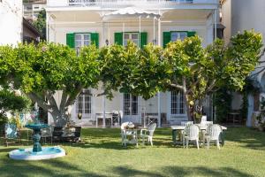 a house with chairs and a table and trees at Villa Amalia Suites Malaga in Málaga