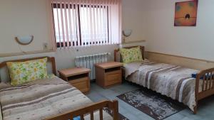 a bedroom with two beds and two tables and a window at Нощувки Ботеви in Shumen
