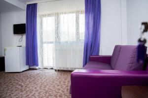 a purple couch in a living room with purple curtains at Vila Alegria in Buşteni