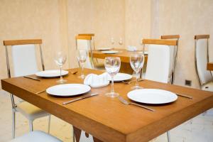 a wooden table with plates and wine glasses on it at AZPETROL HOTEL MINGECHAUR in Mingachevir