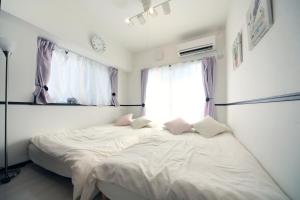 Schlafzimmer mit einem Bett mit weißer Bettwäsche und einem Fenster in der Unterkunft EX Itoman Apartment 501 in Itoman