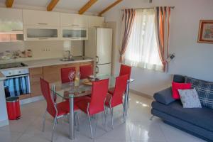 a kitchen and dining room with a glass table and red chairs at Apartments Linda in Stomorska