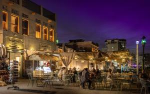 un gruppo di persone seduti ai tavoli in una città di notte di MAZMI CASA a Dubai