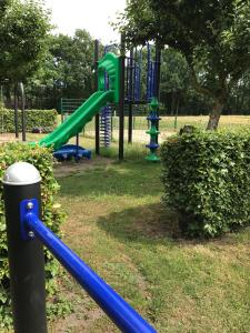 un parque infantil con un tobogán verde y azul en Hotel en B&B Erve Bruggert, en Haaksbergen