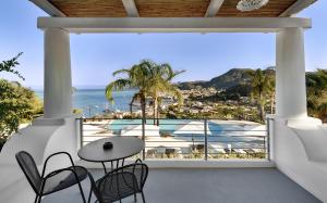 a balcony with a table and chairs and a view of the ocean at Hotel Villa Enrica - Aeolian Charme in Lipari