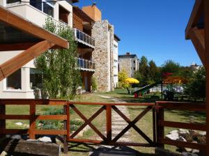 une clôture en bois devant un bâtiment avec une aire de jeux dans l'établissement Terra Magna, à Mar de las Pampas