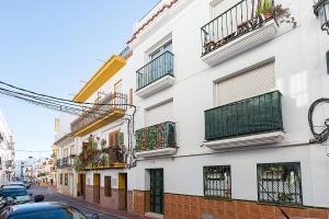 a white building with balconies on a street at Studios Nerja Center C in Nerja