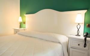 ein Schlafzimmer mit einem großen weißen Bett mit grünen Wänden in der Unterkunft Hotel Villa Enrica - Aeolian Charme in Lipari