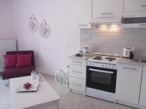 a white kitchen with a stove and a table at Selene's House in Skala Kallirachis