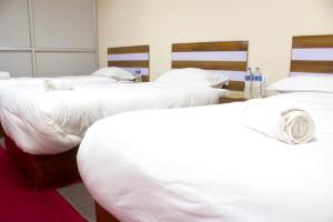 a group of four white beds in a room at Gorkha Chhen bed & breakfast in Gorkhā