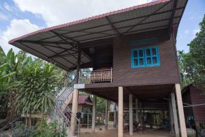 uma casa com uma janela azul e um telhado em Chansor Community Homestay 6 em Phumĭ Trach Pôk (2)