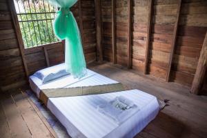 two twin beds in a room with a window at Chansor Community Homestay 6 in Phumĭ Trach Pôk (2)