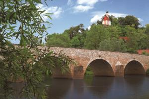 uma ponte de tijolos sobre um rio com uma torre em Landgasthof Schmidbaur em Donauwörth