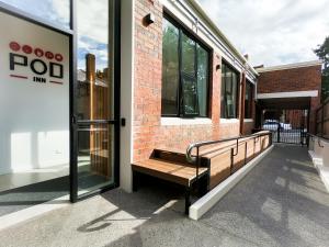 un banc en bois assis à l'extérieur d'un bâtiment dans l'établissement Pod Inn, à Launceston