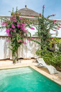 a house with a swimming pool with pink flowers at Keur Dofie in Toubab Dialaw