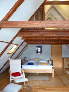 ein Schlafzimmer mit einem Bett und einem Stuhl auf einem Dachboden in der Unterkunft Ein Platz für Ruhe und Naturgenuss in Sebnitz