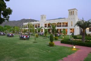 a large white building with tables and chairs in a yard at Aaram Baagh Pushkar by Pachar Group in Pushkar