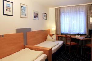 a hotel room with a bed and a desk and a table at Hotel-Landgasthof Grüner Baum - Dittigheim in Tauberbischofsheim