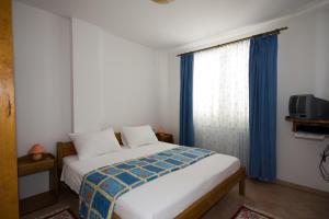 a bedroom with a bed and a window with blue curtains at Apartments Valentino in Vrsar