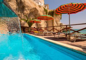 a swimming pool with umbrellas and chairs and the ocean at Hotel Seggio in Vieste