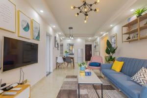 uma sala de estar com um sofá azul e uma televisão em Haikou Meilan·Hainan Univeristy· Locals Apartment 00138360 em Haikou