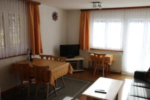 a living room with a table and chairs and a television at Haus Amara in Saas-Grund