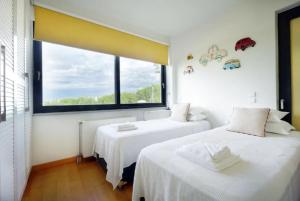 two beds in a room with a large window at Μelpo's House in Kato Daratso