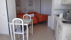 eine Küche mit einem Tisch, 2 Stühlen und einem Bett in der Unterkunft Apartamentos Mediterraneo in Nerja