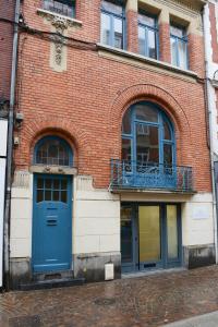 een bakstenen gebouw met blauwe deuren en een balkon bij Lille Avenue in Lille