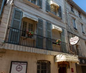 un edificio con ventanas con persianas azules y balcón en Hotel Mignon, en Aviñón