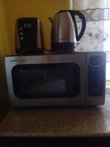 a microwave with a tea pot and a kettle on it at Josan's Haven in Ocho Rios
