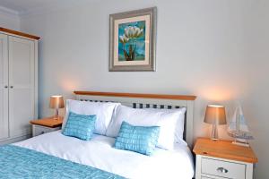 Pacific Heights في إيستبورن: غرفة نوم مع سرير ووسائد زرقاء وبيضاء