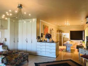 a living room with a kitchen with white cabinets at Villa-Candilabra Guesthouse in Komatipoort