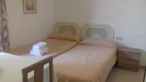 2 Einzelbetten in einem Zimmer mit einem Tisch in der Unterkunft Apartamentos Mediterraneo in Nerja