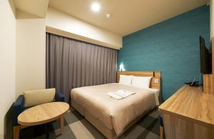 Habitación de hotel con cama y silla en Sotetsu Fresa Inn Osaka Shinsaibashi, en Osaka
